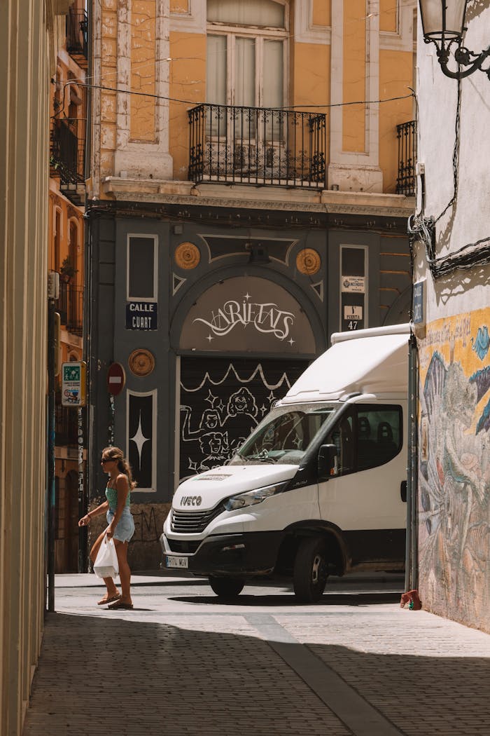 A woman walks near a white van on a vibrant European city street.